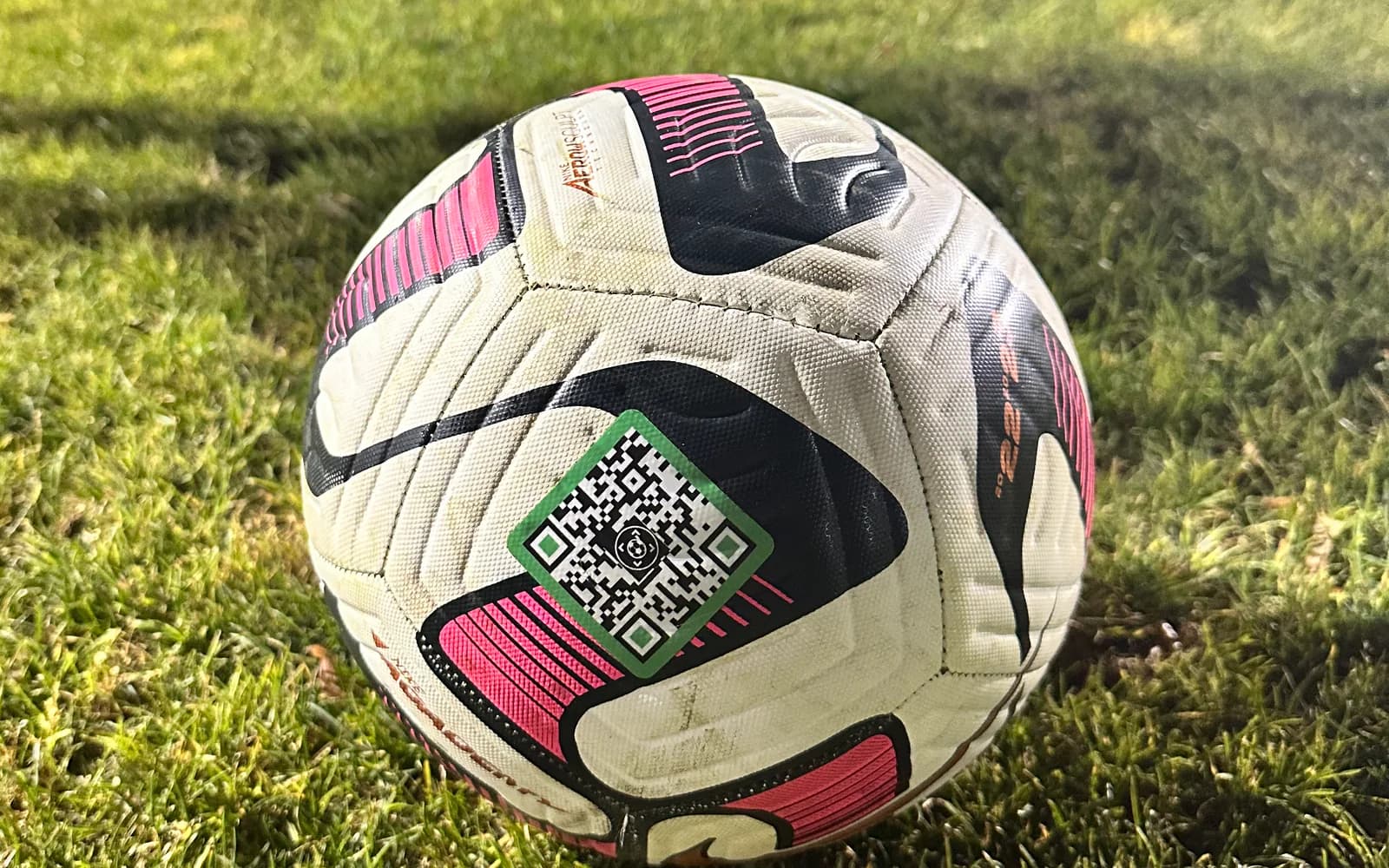 SoccQR tag bonded to a white and pink soccer ball on the field